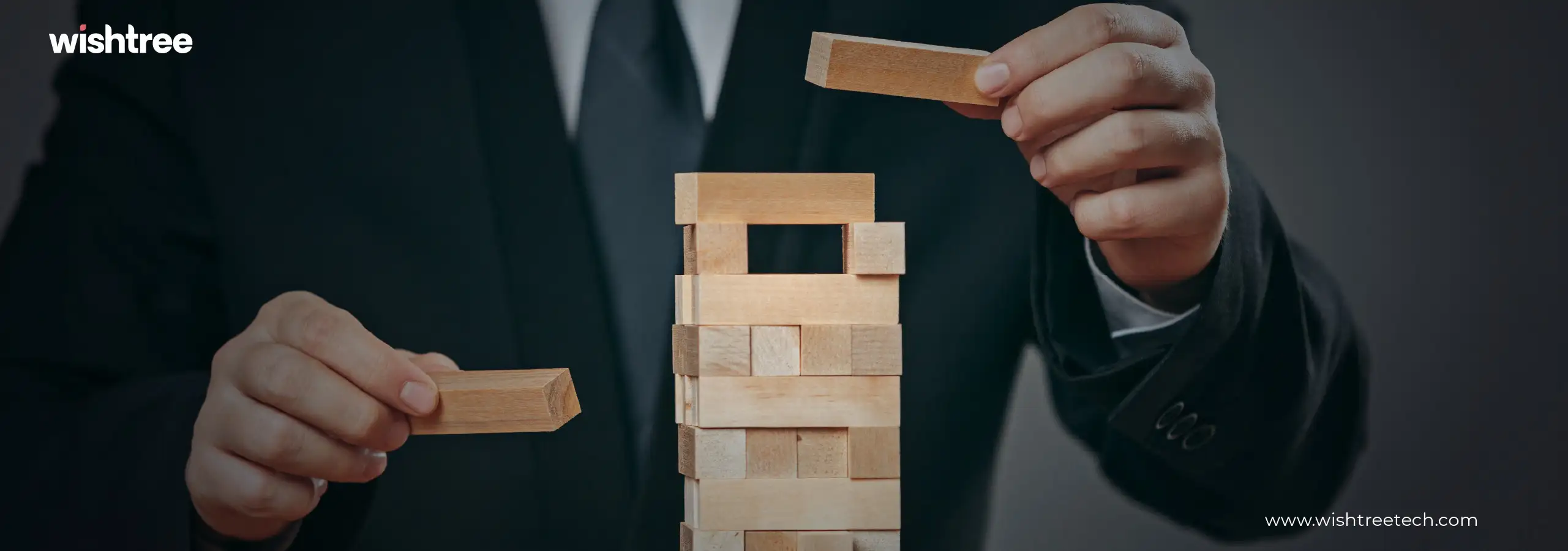 Businessman carefully building a tall structure with wooden blocks.